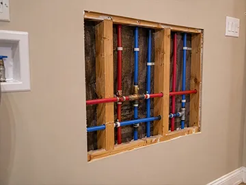 Red and blue PEX water lines exposed behind drywall in a Georgia home.
